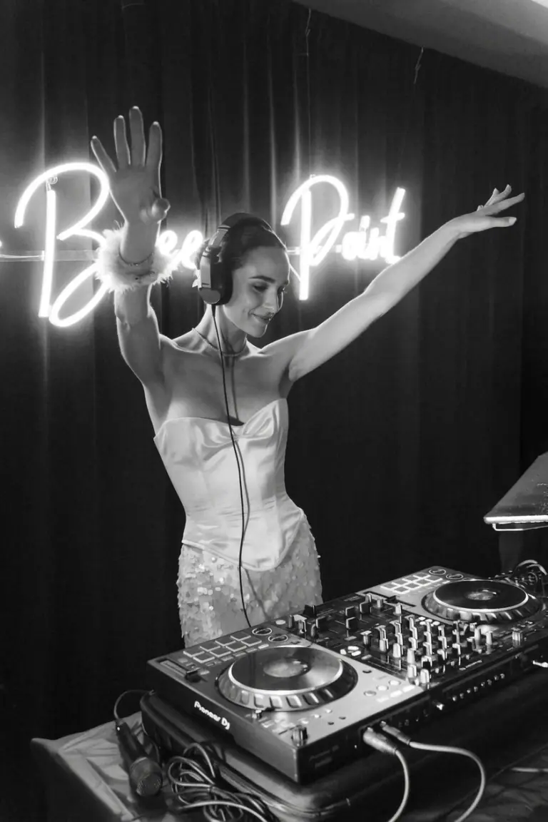 DJ de bodas trabajando en su cabina durante el baile, con la pista llena de invitados